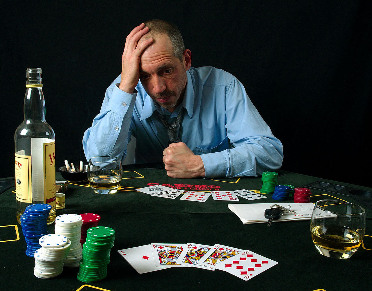 A man at a poker table, with a losing hand in front of him